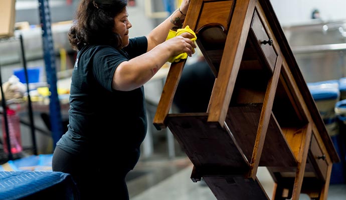 Person cleaning an antique wooden piece of furniture