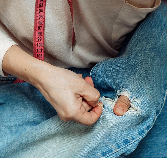 professional worker mending a pair of ripped jeans