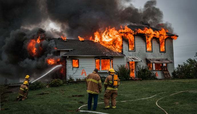 fire fighter trying to control fire of a residential burning house