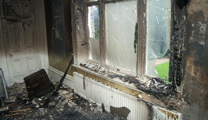 The aftermath of a house fire, with extensive damage visible in a room