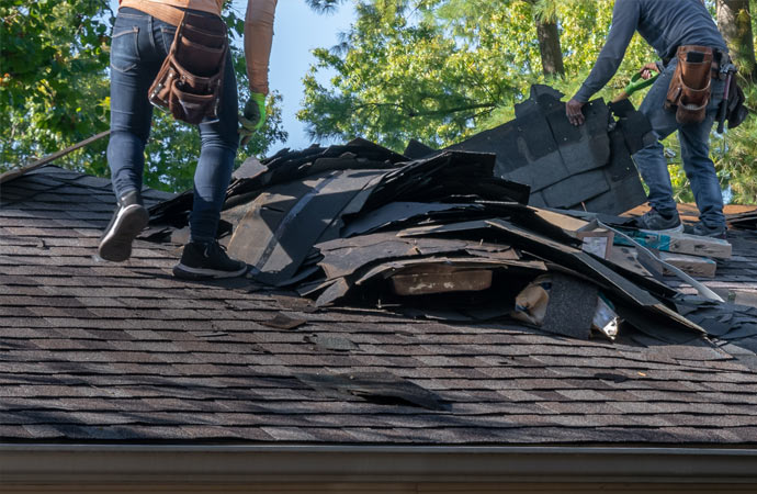 a damaged roof being inspected by two professionals