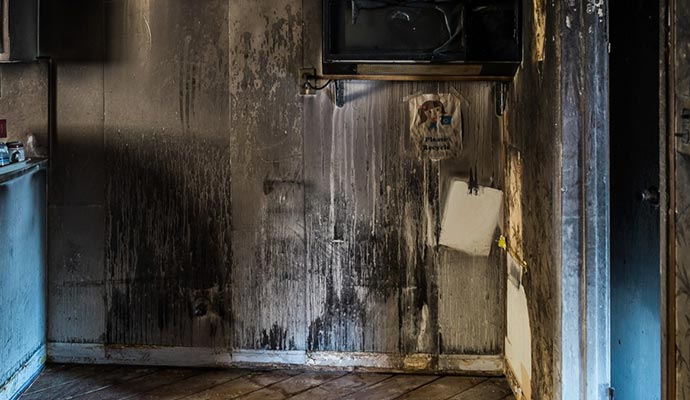 A fire-damaged kitchen with smoke-stained walls