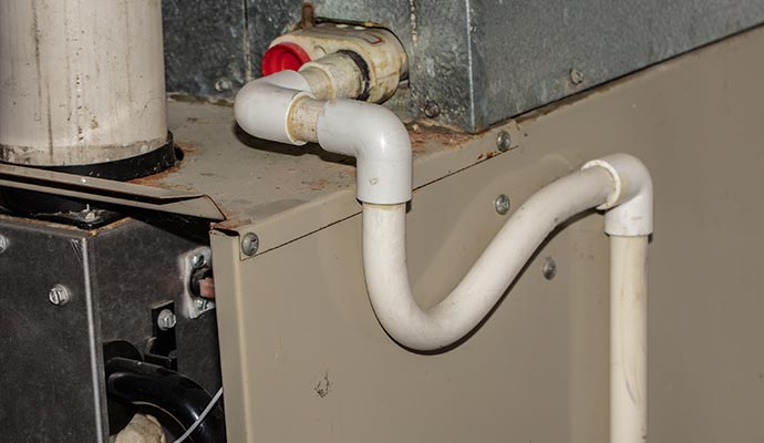 Close-up of an AC condensate drain line with PVC piping