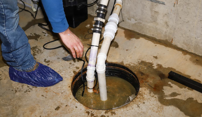 Person inspecting a sump pump in a basement