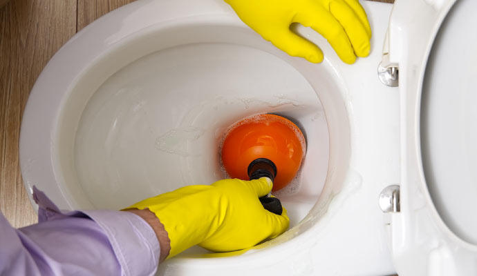 a person unclogging a toilet